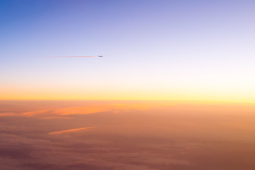 the plane flies in the clouds during sunset