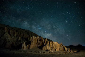 Milky way and late night stars raising over rugged desert landscape