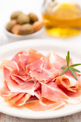 prosciutto on dish with olive oil and olives