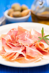 prosciutto on dish with olive oil and olives