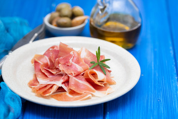 prosciutto on dish with olive oil and olives