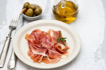 prosciutto on dish with olive oil and olives