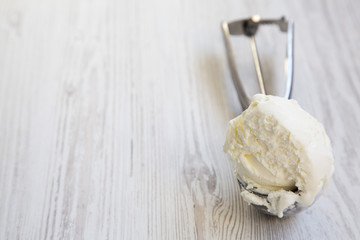 Ice cream in ice cream scoop on white wooden background, close-up. Copy space.