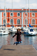 Fototapeta na wymiar Girl jumping in the sun on the dock of a Naples marina