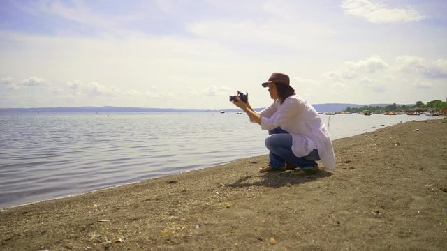 Woman tourist photographer in front of lake in summer