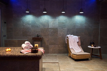 Spa and wellness setting with Rolled spa towels, candles and aroma oil  in a sauna room