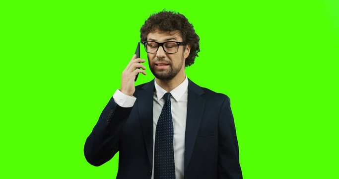 Caucasian nervous businessman in glasses, suit and tie talking angrily on the phone and shouting like a boss. Green screen. Chroma key.