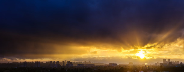 Awesome stunning evening sunset in dramatic sky. Panoramic cityscape big town silhouette in incredibly bright sunshine through hard rain. View to downtown from left bank Dnipro river. Kyiv. Ukraine.