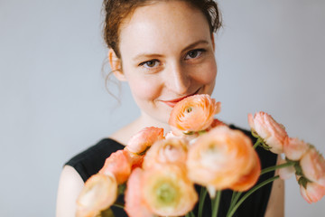 Lächelnde Frau riecht an einem duftenden Strauß Blumen