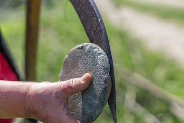 Obraz premium Close-up of hand-sharpening lawn hair. Old hand tool with rusty blade, shallow depth of focus. Concept rustic nostalgia