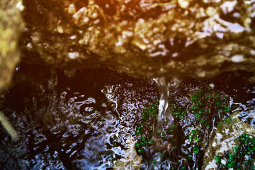 Water colorfully flows down the rocks in the forest, the natural background of the water