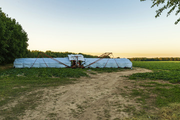 Ein Gurkenflieger zur Ernte von kleinen Gurken steht bei Sonnenuntergang auf einem Feld im  Spreewald