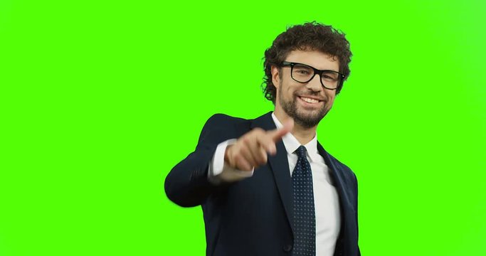 Attractive Caucasian businessman in the suit, tie and glasses smiling and pointing his finger to the camera like you super! On the green screen background. Chroma key.