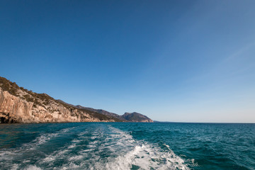 Gulf of Orosei with Cala Gonone and wake behind motor boat