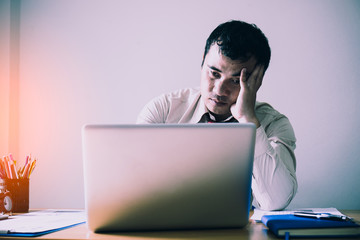 Stressed businessman sitting in office. Hard think on the analysis in the work.