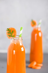 Two bottles with fresh carrot juice and cutted pieces