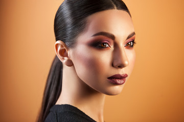a Eurasian girl with sleek hair staring into the distance on an orange background, graceful make-up...