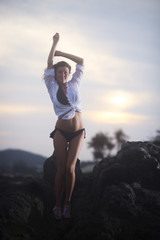 Young beautiful woman posing at sunset standing on stones in the evening