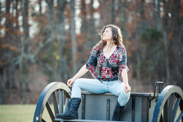 Young happy woman sitting manspreading spreading legs on old cannon carriage in Manassas National Battlefield Park in Virginia where Bull Run battle was fought