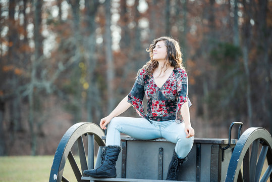 Young happy woman sitting manspreading spreading legs on old cannon carriage in Manassas National Battlefield Park in Virginia where Bull Run battle was fought