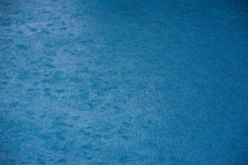 Water with small waves and raindrops on a pool with blue texture background
