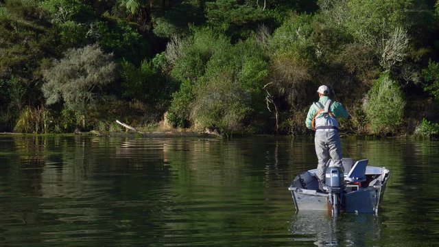 Fisherman fly fishing for trout from a boat on Lake Whakamaru in New Zealand