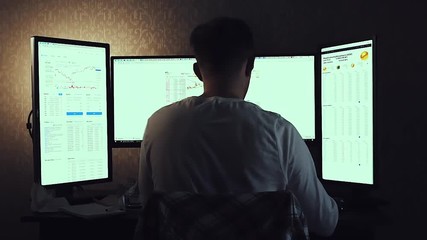 Back view of modern programmer sitting and writing code in dark room. Stock. Young man playing computer games in dark room