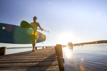 Standup paddler am Steg im Sonnenuntergang