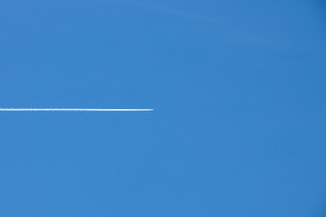 the plane left a white trail on the blue sky