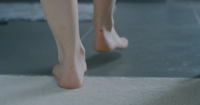 Close up on feet of young woman walking to the shower