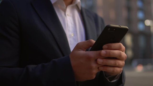 close up businessman holding smartphone unrecognizable man texting message or surfing internet outdoors