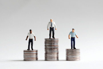 The concept of racism in a company. Miniature people standing on a pile of coins.