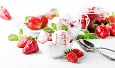 Strawberry ice cream with jam topping, decorated with green mint leaves, gray background, selective focus