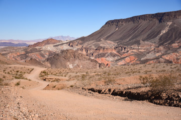 winding dirt road descending into a rugged desert landscape with ancient volcano mountain