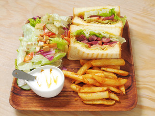 Duck meat sandwich with salad, fries and yogurt on the wooden plate