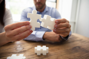 Two Businesspeople Connecting Jigsaw Pieces