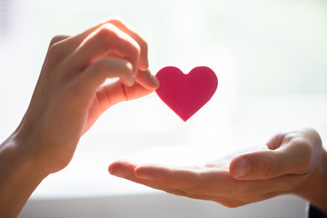 Woman Giving Heart On Man's Hand