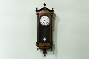 Old wooden pendulum hanging on a wall on blue background.