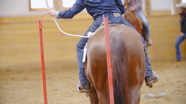 Western rider unhooking rope door long shot in slow motion 4K. An unrecognizable person in focus holding to a rope of a door as part of competition pattern.