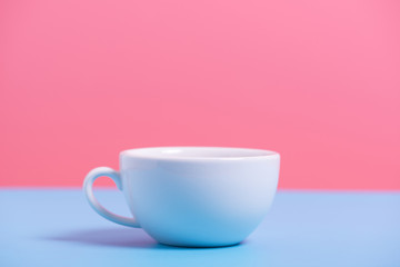 white coffee cup on blue and pink paper , minimal style background