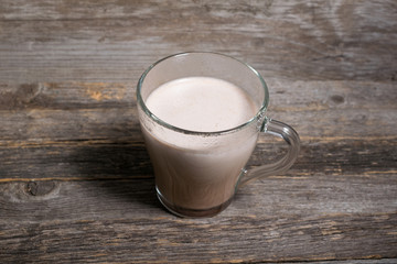 Cocoa drink in glass cup on wooden background. Tasty drink for kids