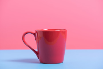 red coffee cup on blue and pink paper , minimal style background