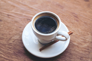 Closeup image of a white cup of hot coffee on vintage wooden table
