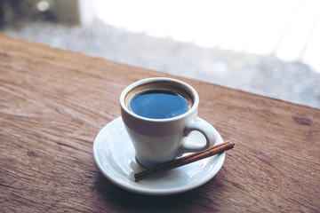Closeup image of a white cup of hot coffee on vintage wooden table