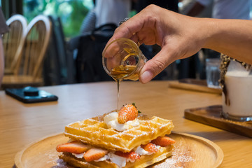 Belgium soft waffles with strawberries with syrup and powdered sugar.