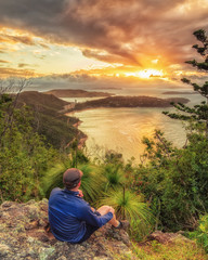 After a hike up Passage Peak on Hamilton Island, a walker rests and watches the sunset