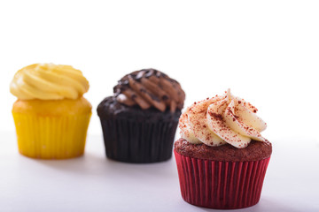 Various cupcakes isolated on white with focus on Red Velvet cupcake