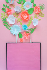 Paper bag of different paper flower on a pink background. Shopping.