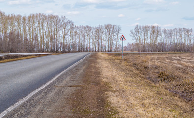 turn of the road with road signs on the spring country road