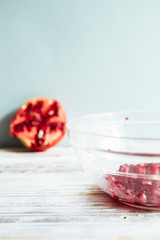 Pomegranate seeds on a glass bowl,on a white wooden board against a blue background